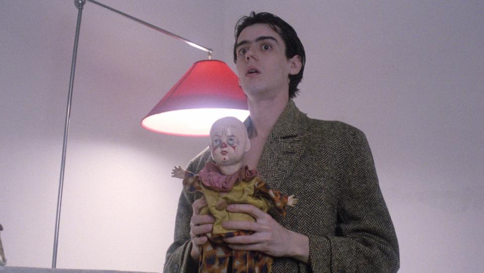 A man holds a creepy doll in a scene from the Spanish film Arrebato.