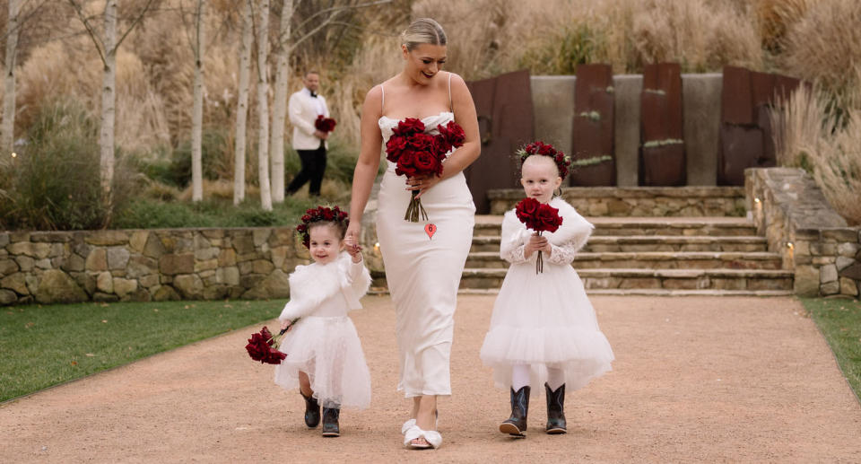 A woman walks down the aisle with two children. 