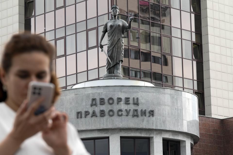 A woman uses her smart phone in front of the court building with the words reading, "Palace of justice," on the front in Yekaterinburg, Russia, Thursday, July 18, 2024, prior to a hearing of Wall Street Journal reporter Evan Gershkovich's suspected spying activities. Gershkovich has attended a hearing behind closed doors in his trial in Russia on espionage charges that he, his employer and the U.S. government vehemently deny. Closing arguments are set for Friday. (AP Photo/Dmitri Lovetsky)