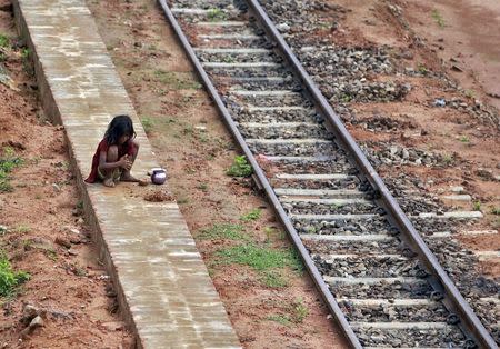 A girl plays with clay next to a railway track on a hot summer day in Agartala, India, May 28, 2015. REUTERS/Jayanta Dey