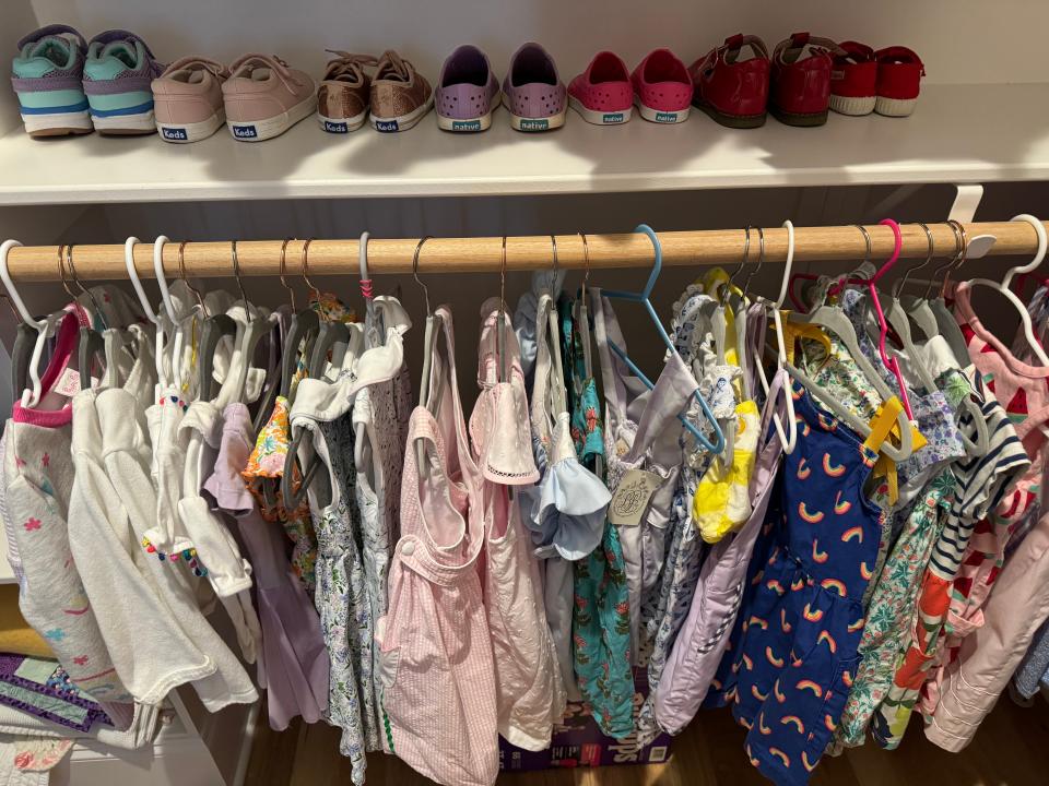 Elliott Harrell's kids' closet with colorful clothes hanging up and shoes on a shelf.