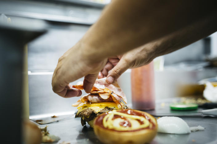 Chef préparant un cheeseburger avec ses mains.