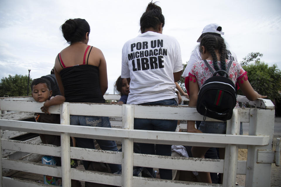 A woman wearing a shirt with the Spanish message "For a free Michoacan" boards a truck with other women, all of whom say they belong to a female-led, self-defense group, at the end of their shift patrolling a checkpoint to protect the entrance of their town of El Terrero in Michoacan state, Mexico, Wednesday, Jan. 13, 2021. Some of the four dozen women warriors are pregnant; some carry their small children to the barricades with them. (AP Photo/Armando Solis)