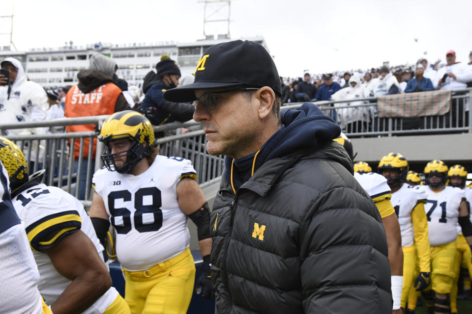 Michigan head coach Jim Harbaugh and his players take the field for an NCAA college football game against Penn State in State College, Pa., Saturday, Nov. 13, 2021 .Michigan defeated Penn State 21-17. (AP Photo/Barry Reeger)
