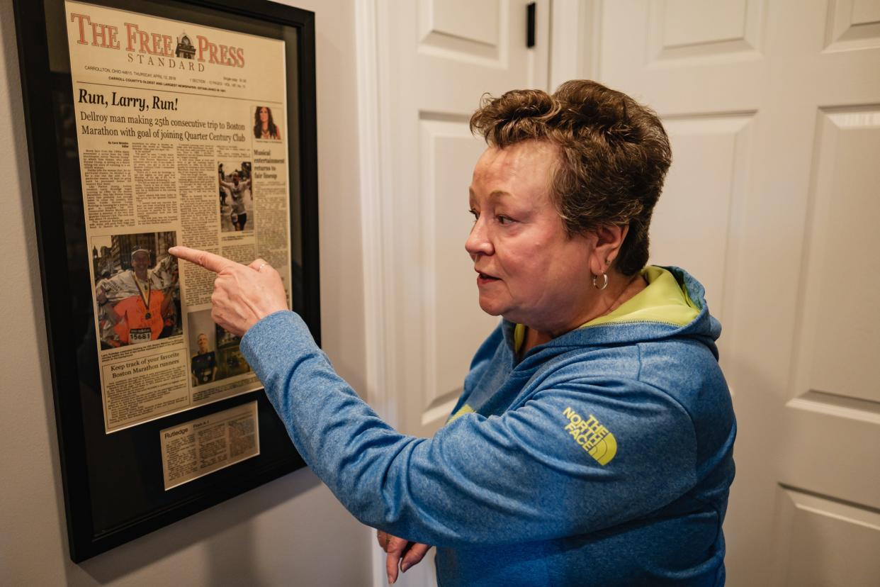 Anita Rutledge talks about a newspaper front which depicts a photograph taken of her husband, Larry, just minutes before the Boston Marathon bombing in 2013, as seen in their Dellory home.