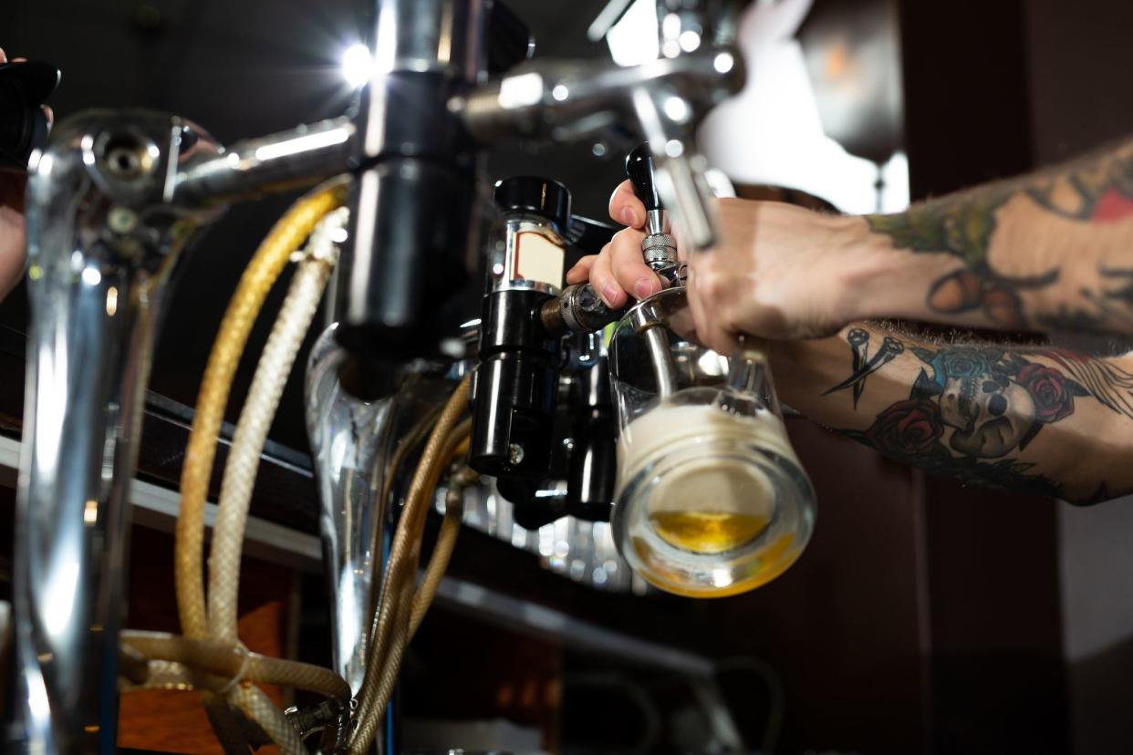 Draft beer pour in a glass from the crane. Waiter pours beer in a pub