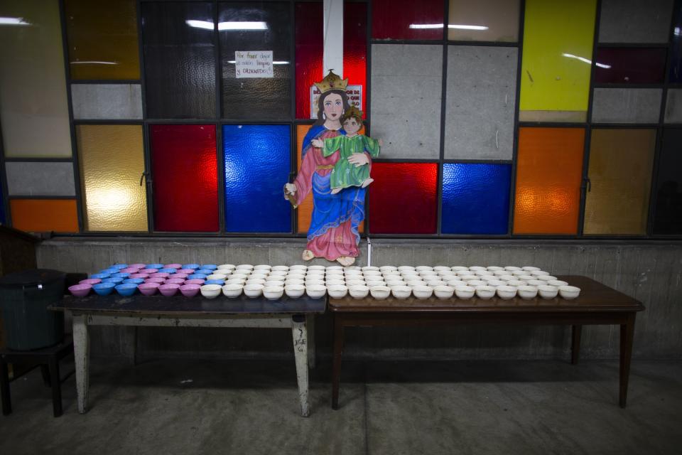 In this Feb. 27, 2020 photo, bowls filled with lentils and rice are lined up on two table tops at a soup kitchen in The Cemetery slum in Caracas, Venezuela. In the midst of a severe crisis, families in Venezuela struggle to consume enough food daily. A recent study by the UN World Food Program reveals that one in three residents of the South American country has difficulty bringing food to the table and fails to meet their basic nutritional requirements. (AP Photo/Ariana Cubillos)