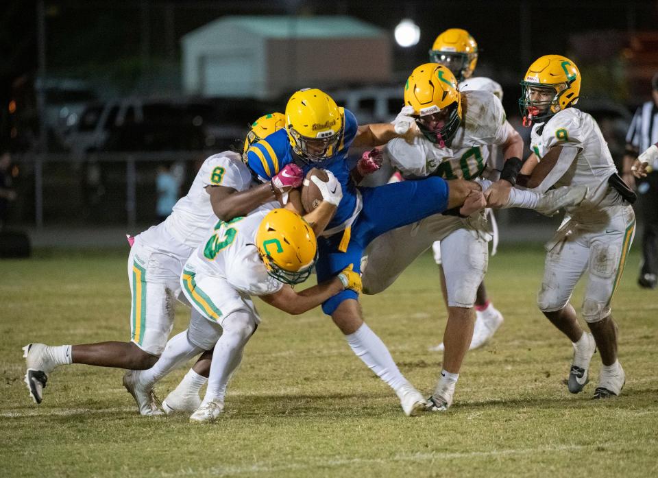 Gulf Breeze's Jake Hooten (No. 4) gets upended by a group of Catholic defensive players before getting wrestled to the ground during Friday night's home game against the Crusaders.