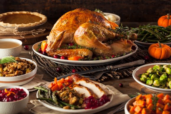 A roasted turkey surrounded by plenty of side dishes and pumpkin pie.