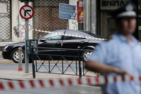 A police officer secures the area around the car of former Greek prime minister and former central bank chief Lucas Papademos following the detonation of an envelope injuring him and his driver, in Athens, Greece, May 25, 2017.