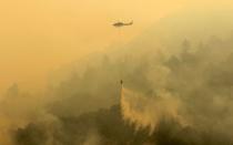 A helicopter makes a water drop during the Soberanes Fire off of Rancho San Carlos Road near Carmel Valley, California, U.S. July 29, 2016. REUTERS/Michael Fiala