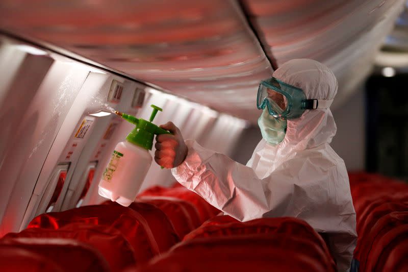 A cleaning worker sprays disinfectant inside the cabin of a Lion Air's Boeing 737-800 at Soekarno-Hatta International Airport