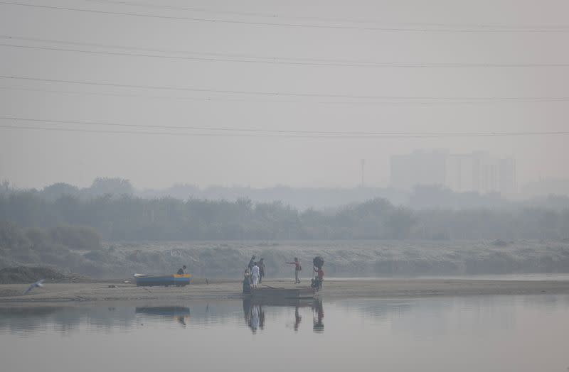 A couple poses during a pre-wedding photo on the banks of Yamuna river on a smoggy morning in the old quarters of Delhi