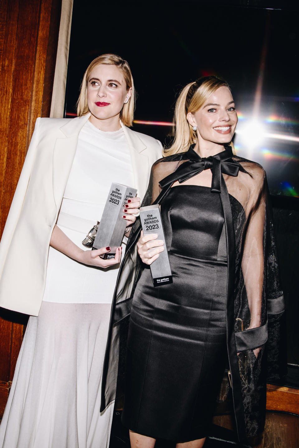 closeup of greta gerwig and margot holding awards