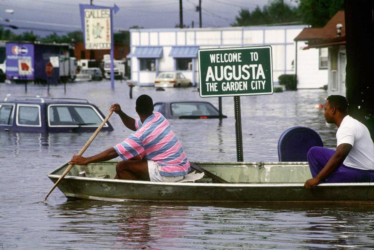 FILE - Two men take a boat into the Laney-Walker neighborhood during the 1990 flood, which was caused by heavy rain inundating the city's inadequate stormwater runoff systems.