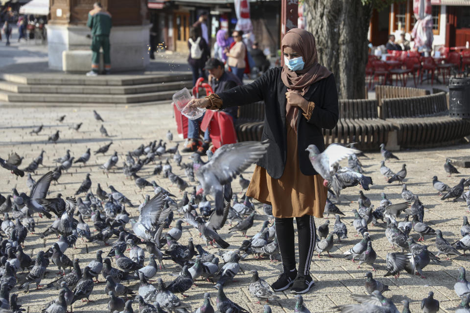 A wearing a face mask feeds pigeons downtown Sarajevo, Bosnia, Monday, Sept. 27, 2021. Public mistrust of authorities in corruption-plagued Bosnia has created an opening for anti-vaccination movement even though the Balkan nation has the highest rate in Europe of coronavirus deaths and faces a growing number of new infections. So far, despite an abundance of coronavirus vaccines in Bosnia, just under 13 percent of its 3.3 million people had been fully immunized against Covid-19. (AP Photo)