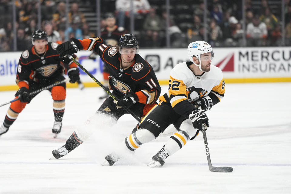 Pittsburgh Penguins' Mark Friedman (52) moves the puck as he is followed by Anaheim Ducks' Trevor Zegras (11) during the first period of an NHL hockey game Friday, Feb. 10, 2023, in Anaheim, Calif. (AP Photo/Jae C. Hong)