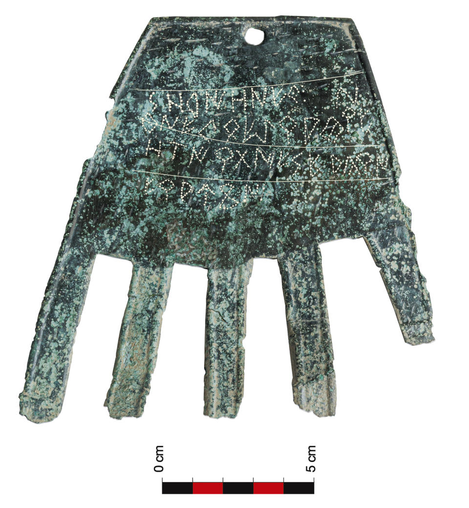 In this undated photo provided by Sociedad de Ciencias Aranzadi, a flat piece of bronze shaped like a human handis displayed in the Navarra region. Investigators in northern Spain believe they have discovered the oldest written record of a precursor of the Basque language, pushing back its earliest evidence to the first century B.C. The Aranzadi Science Society revealed the inscription found on a flat piece of bronze shaped like a human hand that archaeologists unearthed last year. Investigators believe it is the earliest known evidence of a written Vasconic language, the precursor of modern Basque, a minority language still spoken in parts of northern Spain and southwest France. It challenges the wide-held belief the Vascones started writing in their language after the introduction of the Latin script by Roman invaders. (Sociedad de Ciencias Aranzadi via AP)