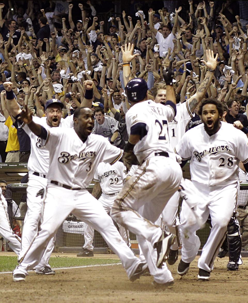 Carlos Gomez (27) is mobbed by teammates as he scored the winning for the Brewers in Game 5 of the National League division series against the Diamondbacks.
