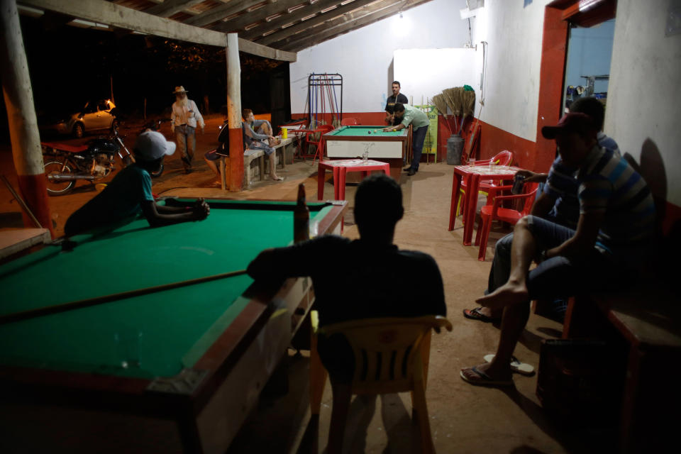 In this March 3, 2014 photo, residents gather for a night of play pool in the Araras community of Brazil's Goias state. Tucked into the sunbaked rolling hills of Brazil's midwest, Araras is home to what is thought to be the largest single group of people suffering from a rare inherited skin disease known as xeroderma pigmentosum, or "XP." (AP Photo/Eraldo Peres)