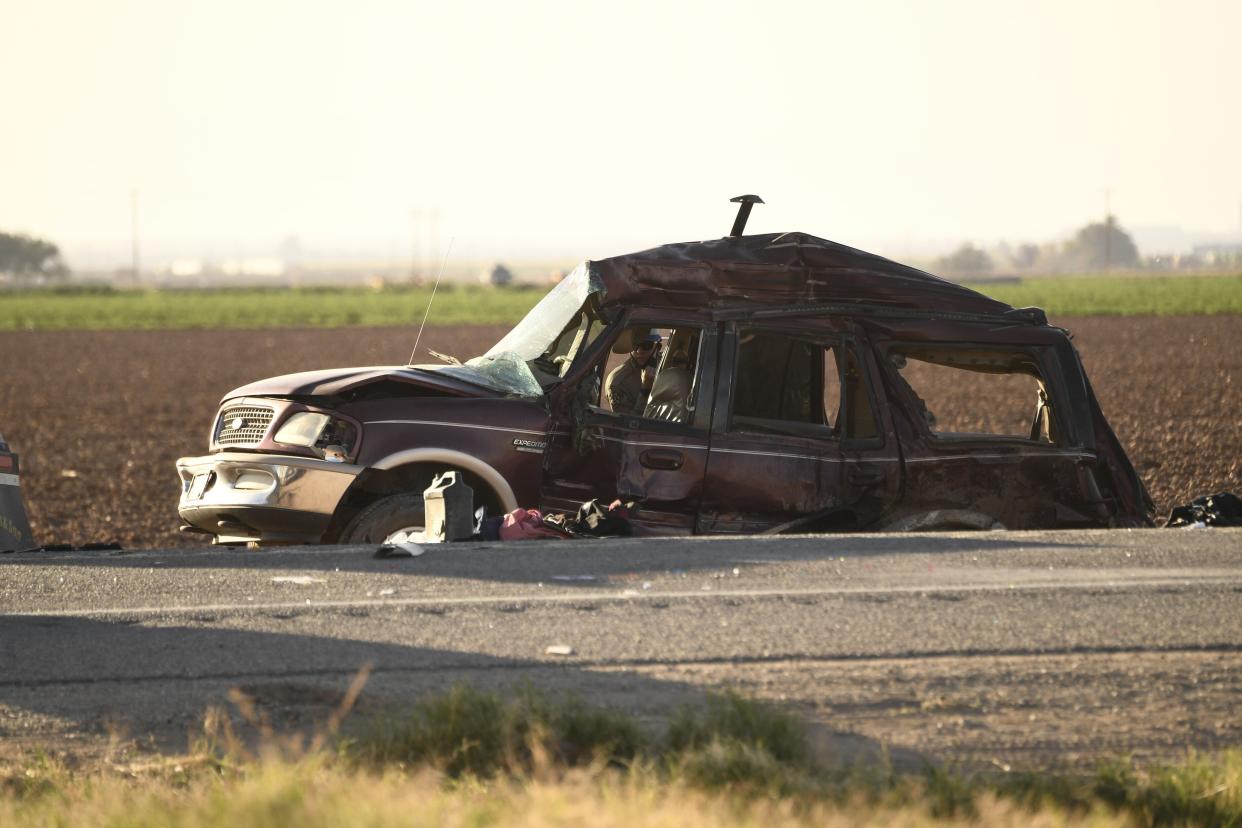 A California Highway Patrol Border Division officer looks inside an SUV that crashed with a semi-truck full of gravel near Holtville, Calif. on March 2, 2021. At least 13 people were killed in southern California on Tuesday when a vehicle packed with passengers, including minors, collided with a large truck close to the Mexico border, officials said.