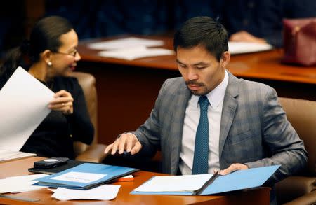 Philippine Senator and boxing champion Manny Pacquiao reads his briefing materials next to fellow Senator Grace Poe, as he prepares for the Senate session in Pasay city, Metro Manila, Philippines September 20, 2016. Picture taken September 20, 2016. REUTERS/Erik De Castro