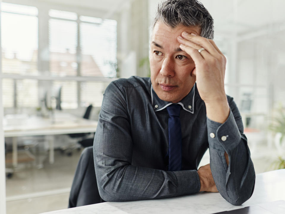 person sitting at their desk with their hand on their head