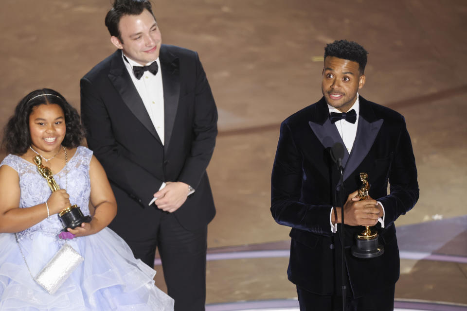 L-R Film subject Porché Brinker and directors Ben Proudfoot and Kris Bowers on stage after 'The Last Repair Shop' wins the Oscar for Best Doc Short.