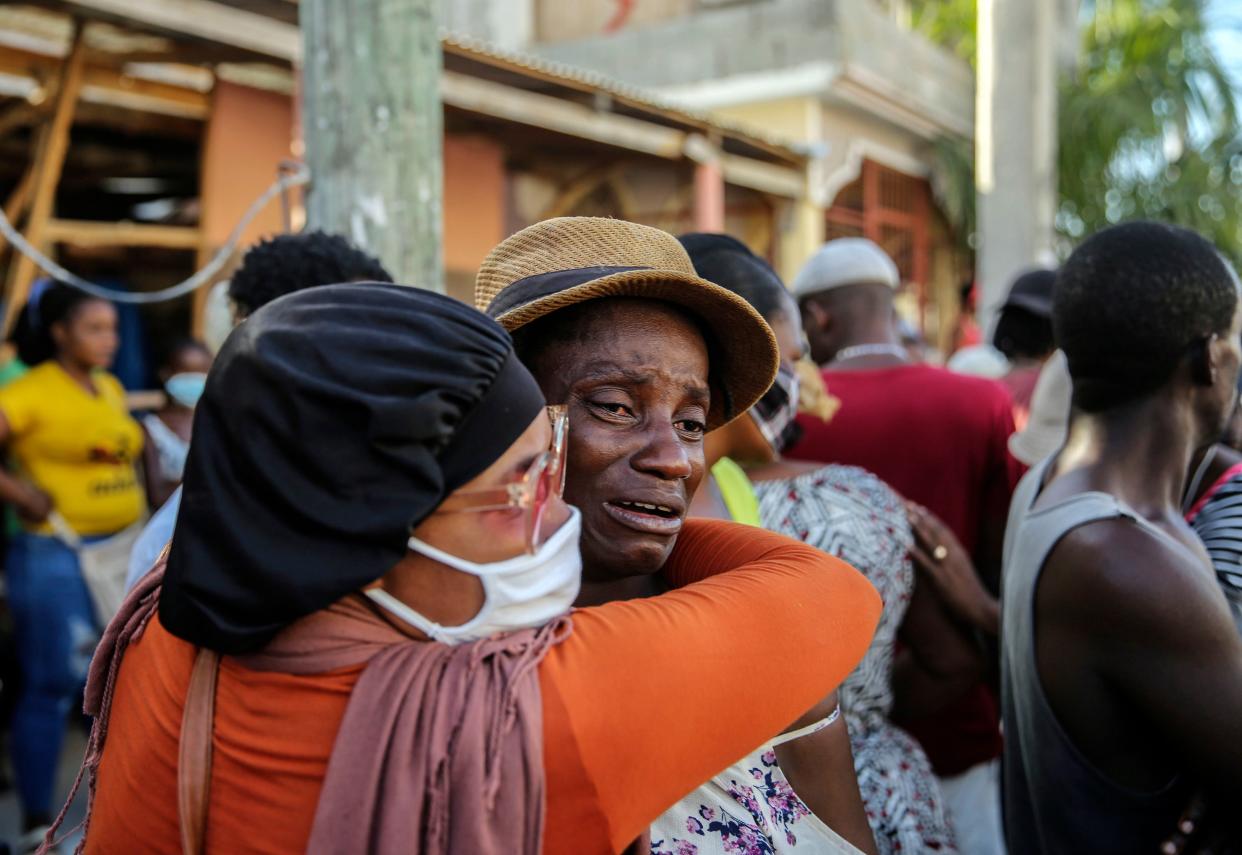 People cry during the search for those who are still missing in a house destroyed by the earthquake in Les Cayes, Haiti, Sunday, Aug. 15, 2021.