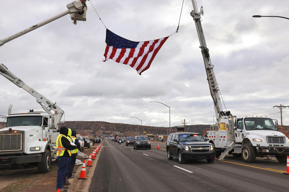 In this photo provided by the Navajo Nation Office of the President and Vice President, tribal utility workers hiost a flag above a funeral procession route for former Navajo President Peterson Zah on the reservation in northeastern Arizona on Saturday, March 11, 2023. Zah was the first president elected on the Navajo Nation in the 1990 after the tribe restructured its government into three branches to prevent power from being concentrated in the chairmanship. (Larry Price/Navajo Nation Office of the President and Vice President via AP)