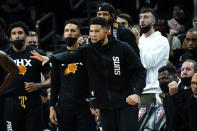 Phoenix Suns guard Devin Booker cheers from the bench during the second half of an NBA basketball game against the Golden State Warriors, Tuesday, Nov. 30, 2021, in Phoenix. Booker did not play in the second half. The Suns won 104-96. (AP Photo/Matt York)