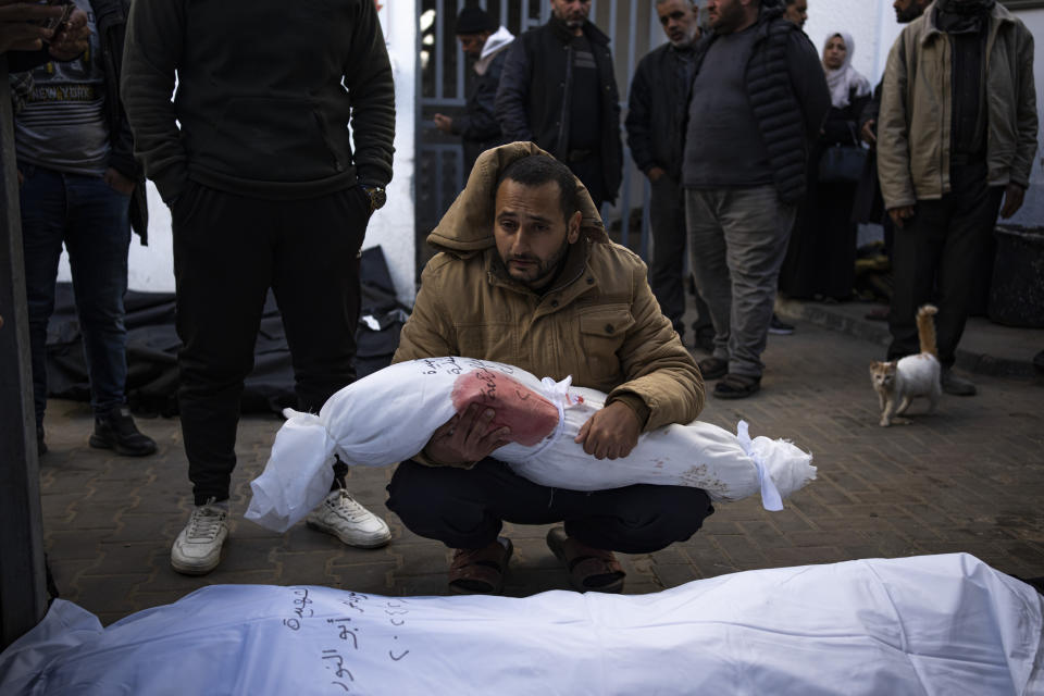 A man holds the body of his daughter who was killed in the Israeli bombardment of the Gaza Strip, at a hospital morgue in Rafah, Wednesday, Feb. 21, 2024. (AP Photo/Fatima Shbair)