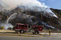 Firefighters begin hosing down the flames of a wildfire called the Palisades Fire minutes after it ignites on Monday, Oct. 21, 2019 in Pacific Palisades, a suburb of Los Angeles. A furious firefighting air and ground attack beat back the wildfire Monday as it raced up canyon walls toward multimillion-dollar ocean-view homes on a ridge in Los Angeles. (AP Photo/Christian Monterrosa)