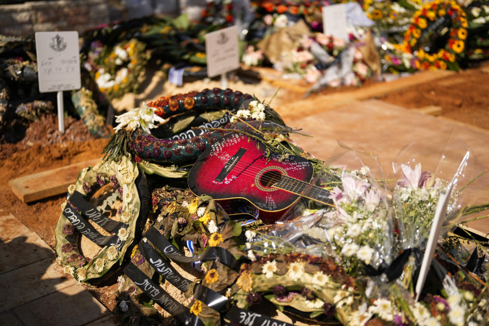 Una guitarra y coronas de flores se ven en la tumba del soldado Ilai Azar tras su funeral en el cementerio de Kiryat Shaul en Tel Aviv, Israel, el sábado 14 de octubre de 2023. (AP Foto/Francisco Seco)