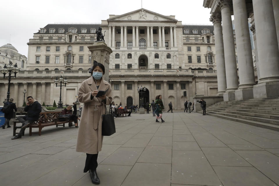 A pedestrian wearing face masks walk past the Bank of England in London, Wednesday, March 11, 2020. Britain's Chancellor of the Exchequer Rishi Sunak will announce the first budget since Britain left the European Union. (AP Photo/Matt Dunham)