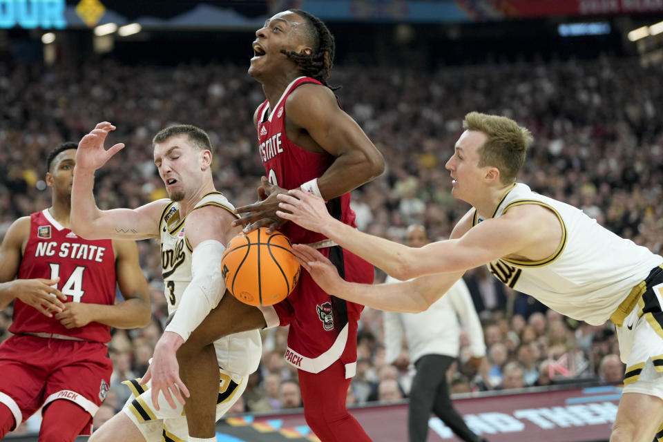North Carolina State guard DJ Horne (0) drives to the basket between Purdue guard Braden Smith (3) and guard Fletcher Loyer (2) during the second half of the NCAA college basketball game at the Final Four, Saturday, April 6, 2024, in Glendale, Ariz. (AP Photo/David J. Phillip)
