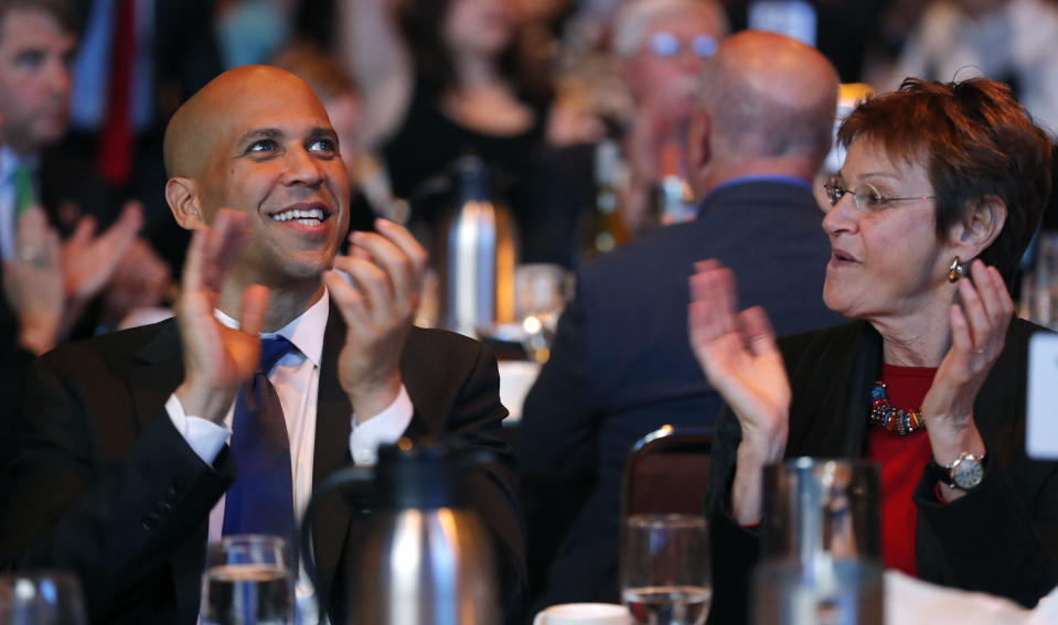 FILE - In this Saturday, Oct. 6, 2018, file photo, U.S. Sen. Cory Booker, D-N.J., sits with former Iowa Lt. Gov. Sally Pederson, right, during the Iowa Democratic Party's annual Fall Gala, in Des Moines, Iowa. Many of the Democratic Party’s most ambitious have begun building relationships in the states most responsible for picking the party’s next presidential nominee. Booker has raised more than $7 million and campaigned across 21 states for other Democratic candidates this midterm season, according to an aide. (AP Photo/Charlie Neibergall, File)