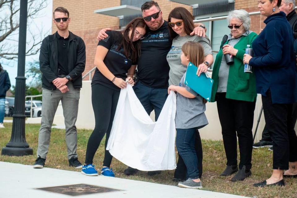 Members of Branden Estorffe’s family remove a sheet covering a metal star during a ceremony dedicating commemorative stars in honor of Sergeant Steven Robin and Officer Branden Estorffe outside the new Bay St. Louis Police Department in Bay St. Louis on Thursday, Dec. 14, 2023. Estorffe and Robin were killed on Dec. 14, 2022 by a local veterinarian when they responded to a call at a Motel 6.