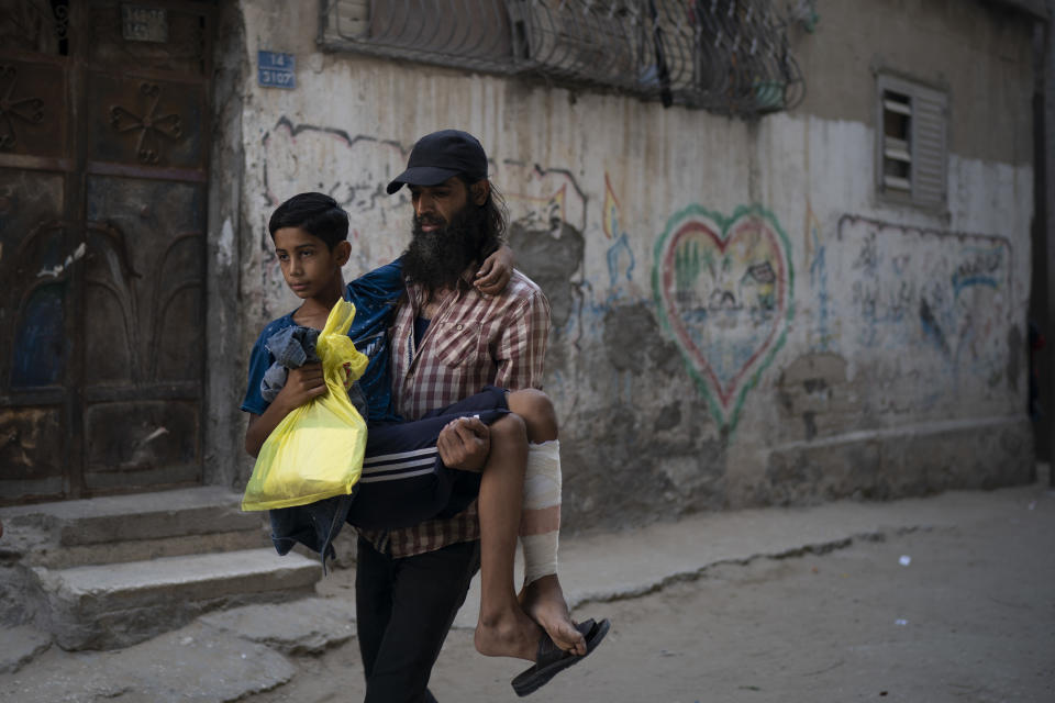 In this Sept. 16, 2018, photo, Raed Abu Khader, right, carries his 12-year-old son Mohammed as they return from the hospital in Gaza City. Mohammed was shot in the leg at one of the demonstrations on Gaza strip's border with Israel. Ever since Hamas launched demonstrations in March against Israel's blockade of Gaza, children have been a constant presence in the crowds. Since then, U.N. figures show that 948 children under 18 have been shot by Israeli forces and 2,295 have been hospitalized, including 17 who have had a limb amputated. (AP Photo/Felipe Dana)
