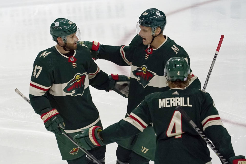 Minnesota Wild's Alex Goligoski, left, is congratulated by Nick Bjugstad, center, after Goligoski's goal against Winnipeg Jets goalie Connor Hellebuyck in the first period of an NHL hockey game, Friday, Nov. 26, 2021, in St. Paul, Minn. (AP Photo/Jim Mone)