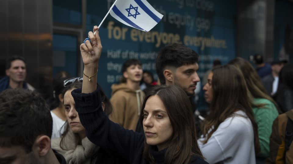 A person holds an Israeli flag as opposing groups protest near the Israeli consulate in New York City on October 8. - Adam Gray/Getty Images