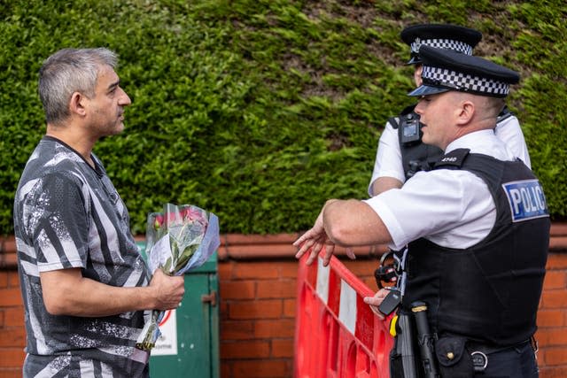 A man arrives to leave a floral tribute near Hart Street in Southport 