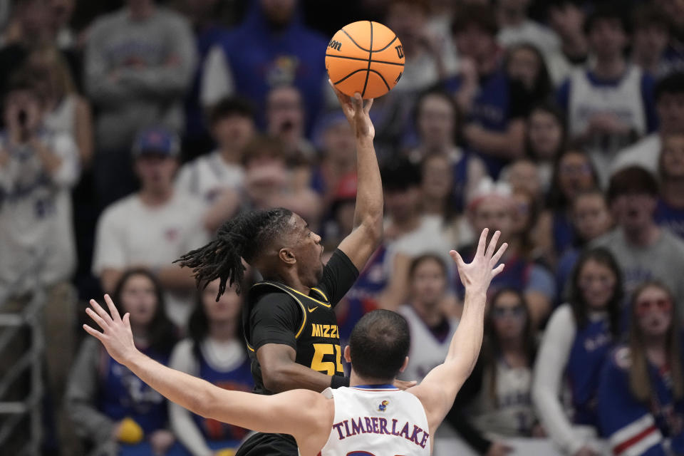 Missouri guard Sean East II (55) gets past Kansas guard Nicolas Timberlake (25) to put up a shot during the first half of an NCAA college basketball game Saturday, Dec. 9, 2023, in Lawrence, Kan. (AP Photo/Charlie Riedel)