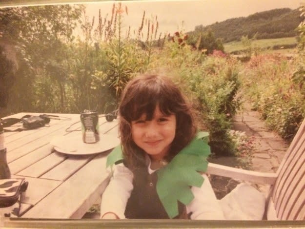 Young child sitting at a table outside and wearing a Robin Hood cloak