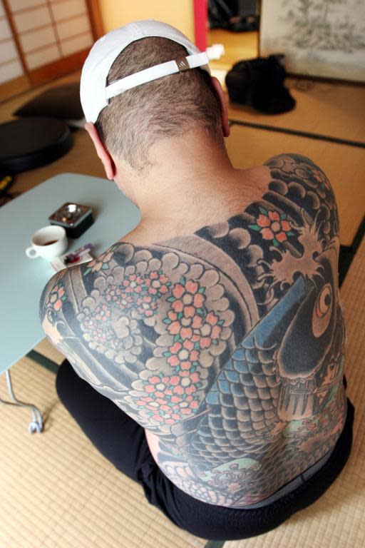 A retired Japanese yakuza crime boss shows the tattoo on his back featuring a carp swimming up a waterfall, at his home in Tokyo on March 20, 2009