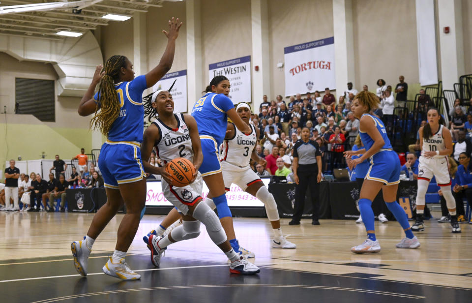 UConn's KK Arnold (2) drives to the basket between UCLA's Charisma Osborne, left, and Lauren Betts during the first half of an NCAA college basketball game at the Cayman Islands Classic in George Town, Cayman Islands, Friday, Nov. 24, 2023. (AP Photo/Kevin Morales)