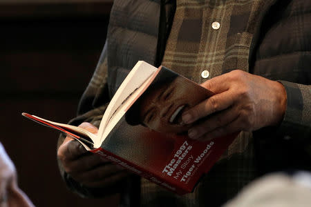 A man reads Golfer Tiger Woods' new book "The 1997 Masters: My Story" as he waits at a book signing event with Woods at a Barnes & Noble store in New York City, New York, U.S., March 20, 2017. REUTERS/Mike Segar