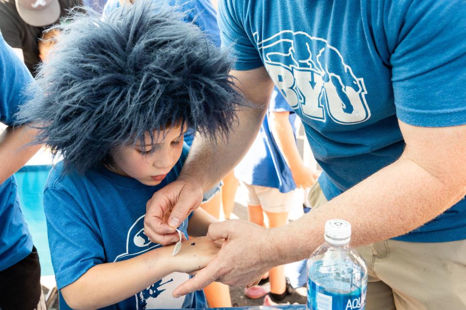 Chris Jackson helps his son Blake apply temporary tattoos with Brigham Young University’s logo before the game against Southern Utah University at LaVell Edwards Stadium in Provo on Saturday, Sept. 9, 2023. | Megan Nielsen, Deseret News