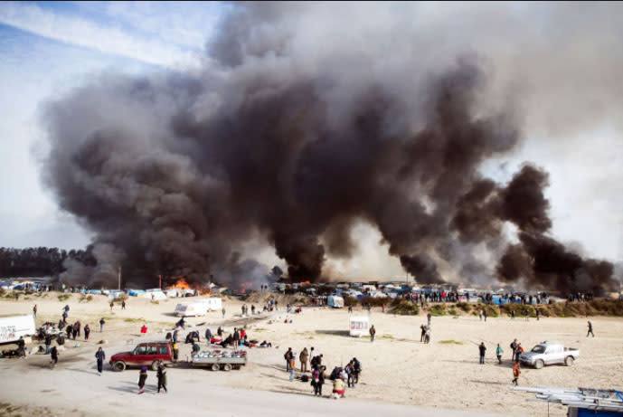 Dichte Rauchschwaden ziehen über der Notunterkunft in Calais. Hilfsorganisationen gehen davon aus, dass bis zu 8.000 Menschen in dem Flüchtlingslager gelebt haben. Bislang sollen bereits 4.000 evakuiert und in über 450 Ausweichlager gebracht worden sein. (Foto: Etienne Laurent/EPA)