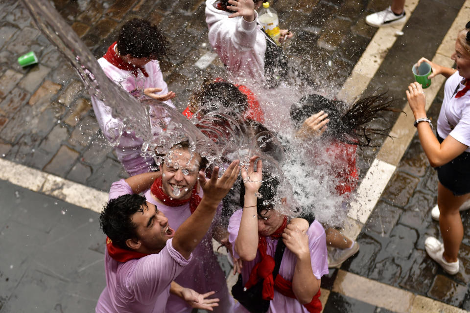 Water is thrown on revelers celebrating the launch of the 'Chupinazo' rocket, to mark the official opening of the 2022 San Fermin fiestas in Pamplona, Spain, Wednesday, July 6, 2022. The blast of a traditional firework opened Wednesday nine days of uninterrupted partying in Pamplona's famed running-of-the-bulls festival which was suspended for the past two years because of the coronavirus pandemic. (AP Photo/Alvaro Barrientos)